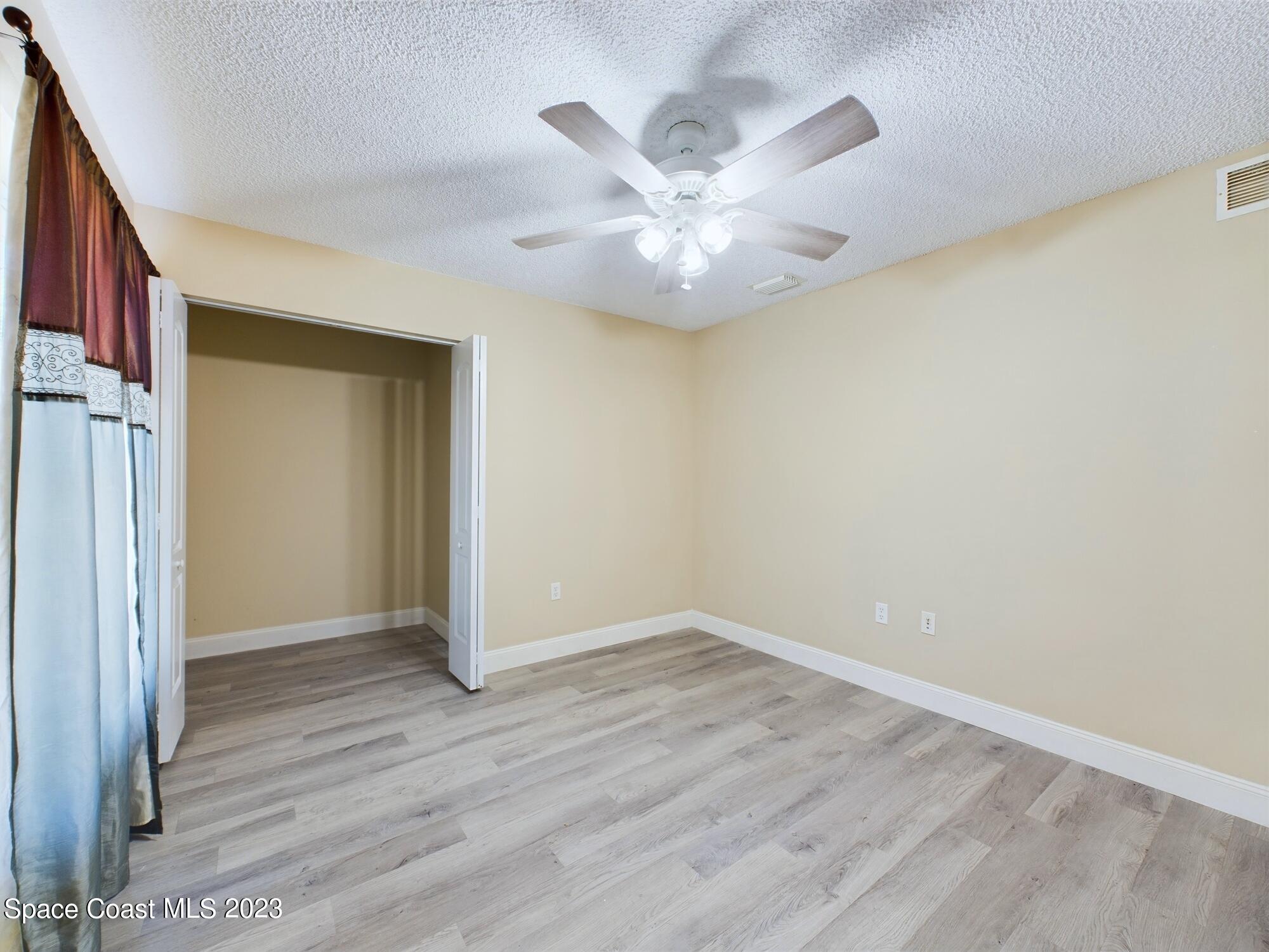 248 Benchor Road Northwest Palm Bay, FL 32907 - Photo 18 of 31 an empty room with wooden floor fan and windows