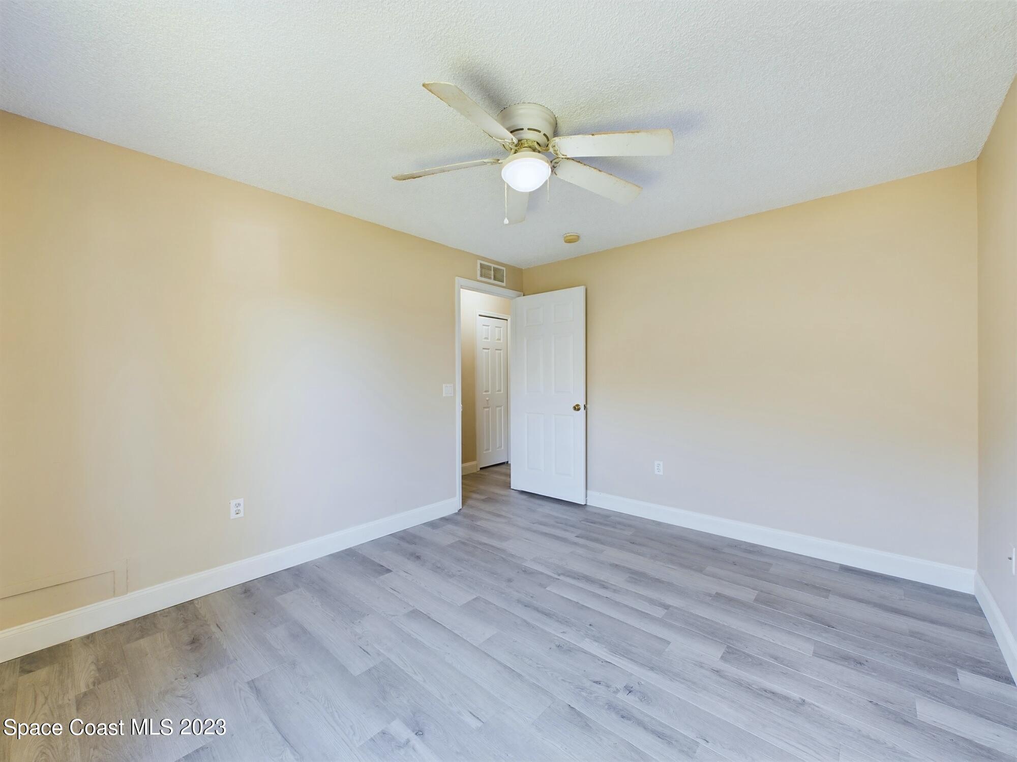 248 Benchor Road Northwest Palm Bay, FL 32907 - Photo 20 of 31 a view of an empty room with wooden floor and a ceiling fan