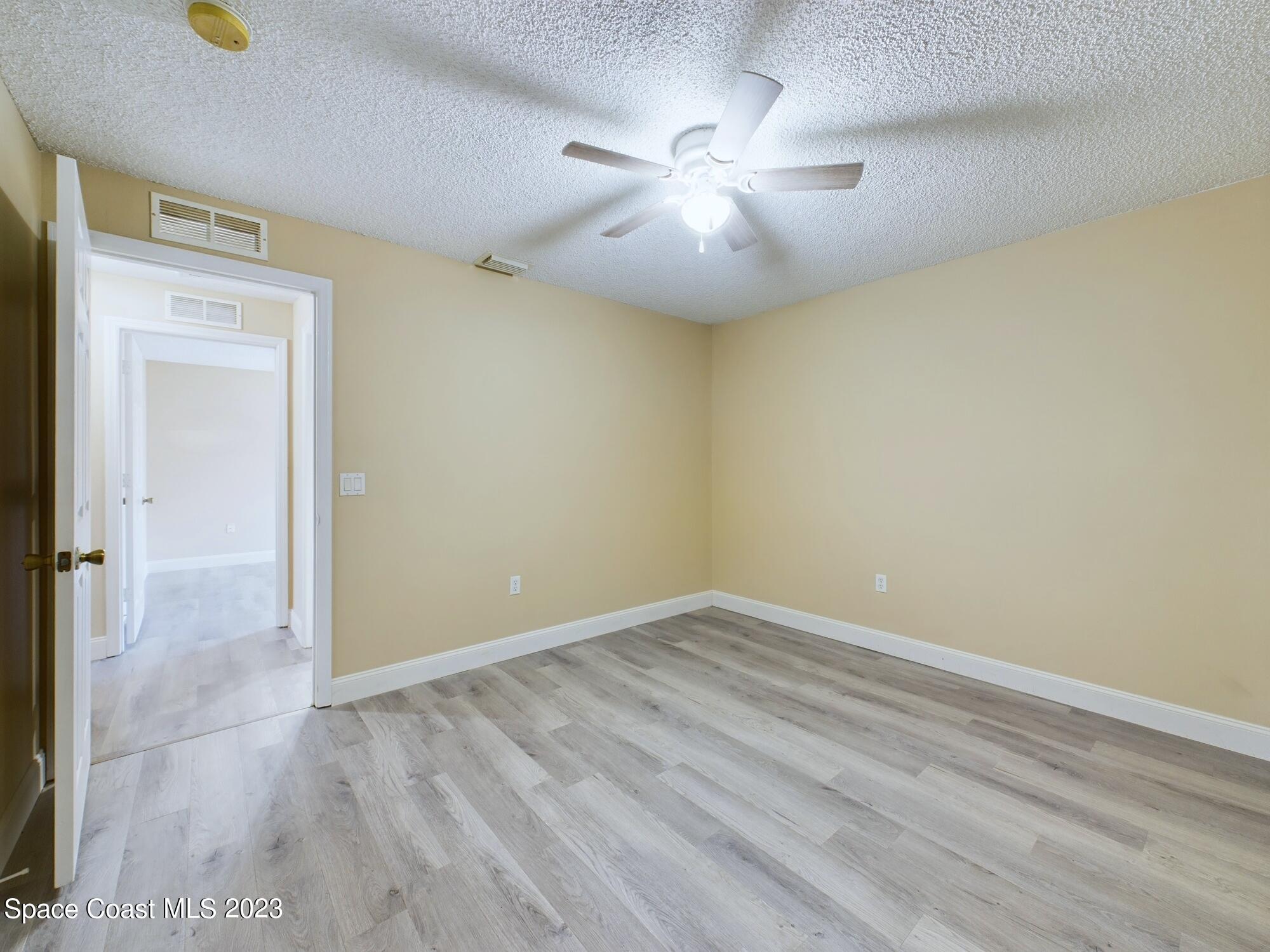 248 Benchor Road Northwest Palm Bay, FL 32907 - Photo 23 of 31 an empty room with a chandelier fan and windows