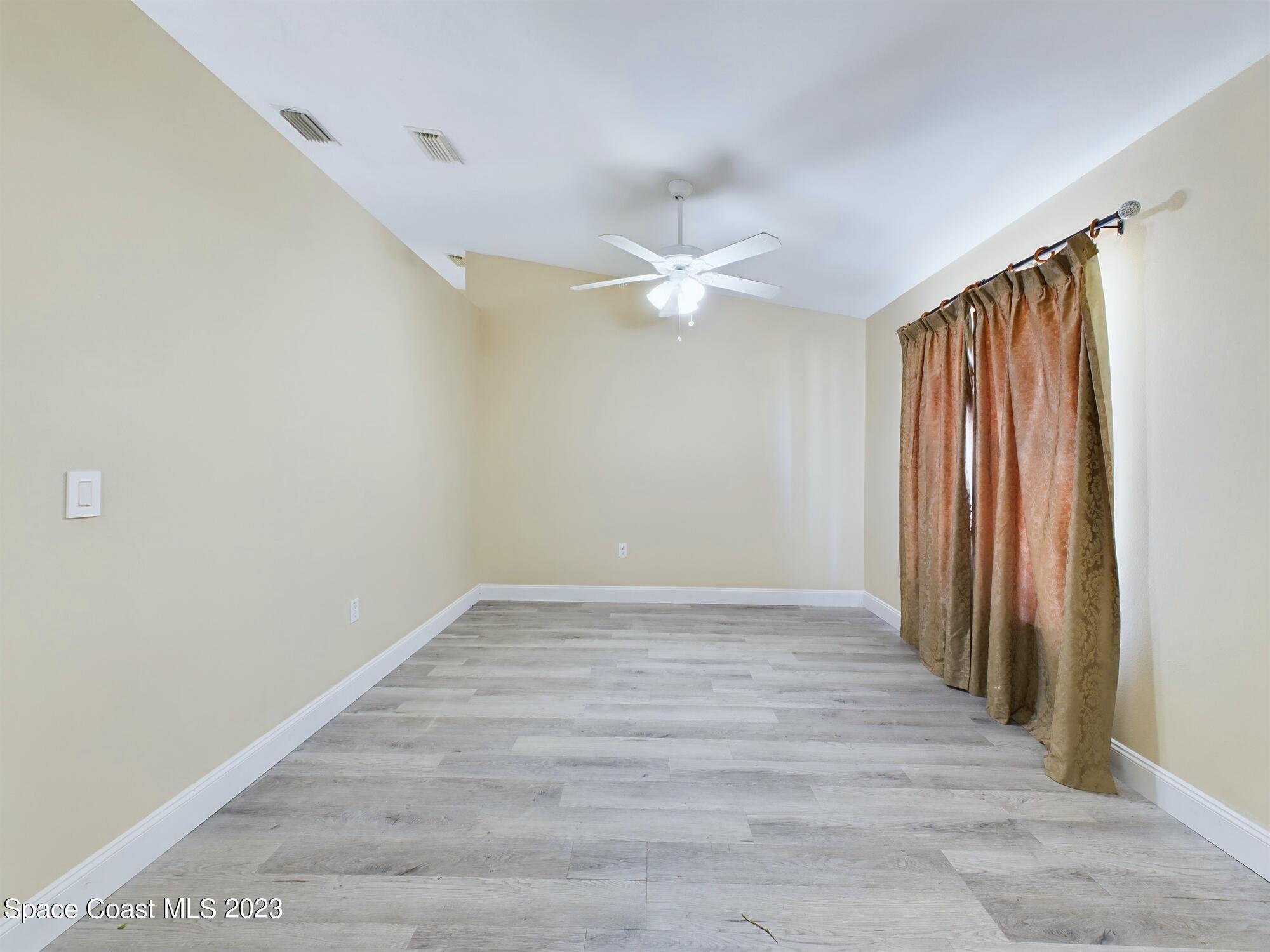 248 Benchor Road Northwest Palm Bay, FL 32907 - Photo 4 of 31 an empty room with wooden floor and fan