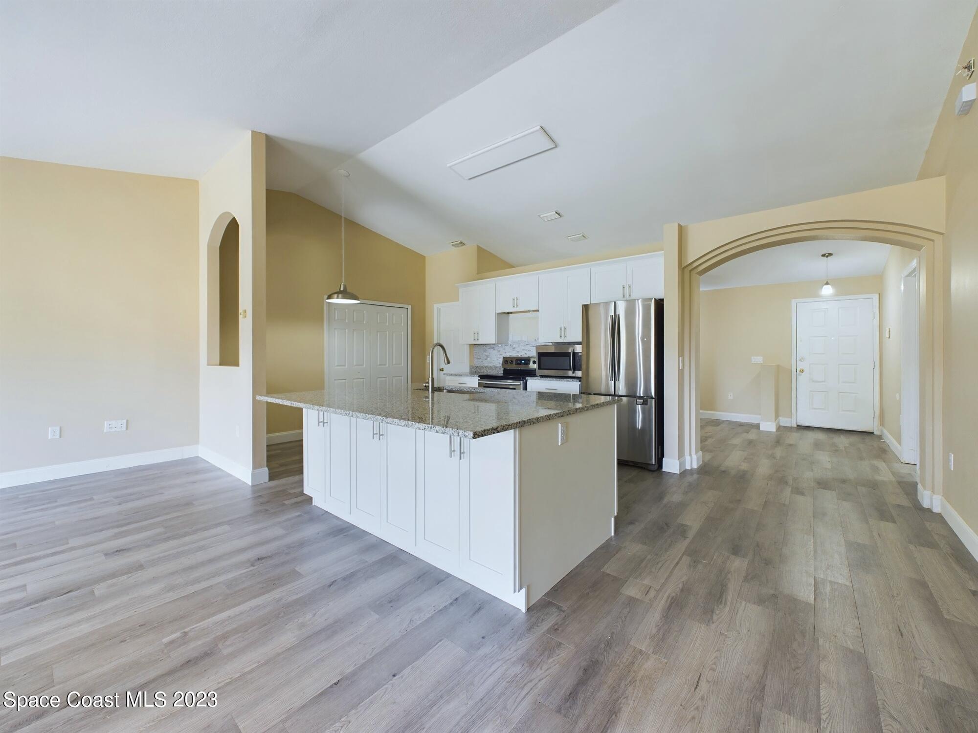 248 Benchor Road Northwest Palm Bay, FL 32907 - Photo 6 of 31 a large kitchen with a center island wooden floor stainless steel appliances and cabinets