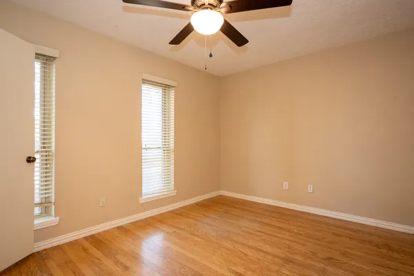 a view of an empty room with window and wooden floor