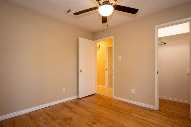 an empty room with wooden floor and fan