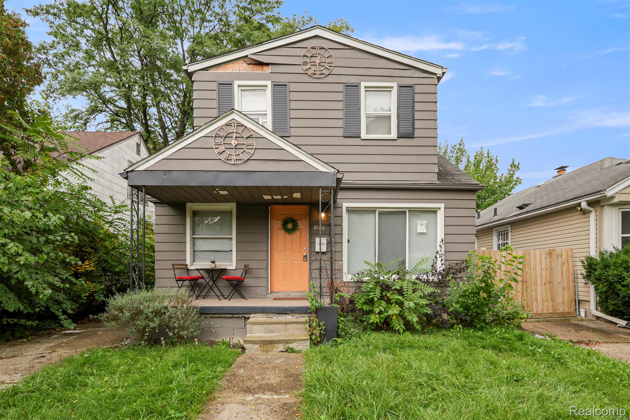 6780 Rutland Street Detroit, MI 48228 - Photo 1 of 35 Gable roofline, prominent front porch, gray siding, white window trim, and a vibrant orange entry door