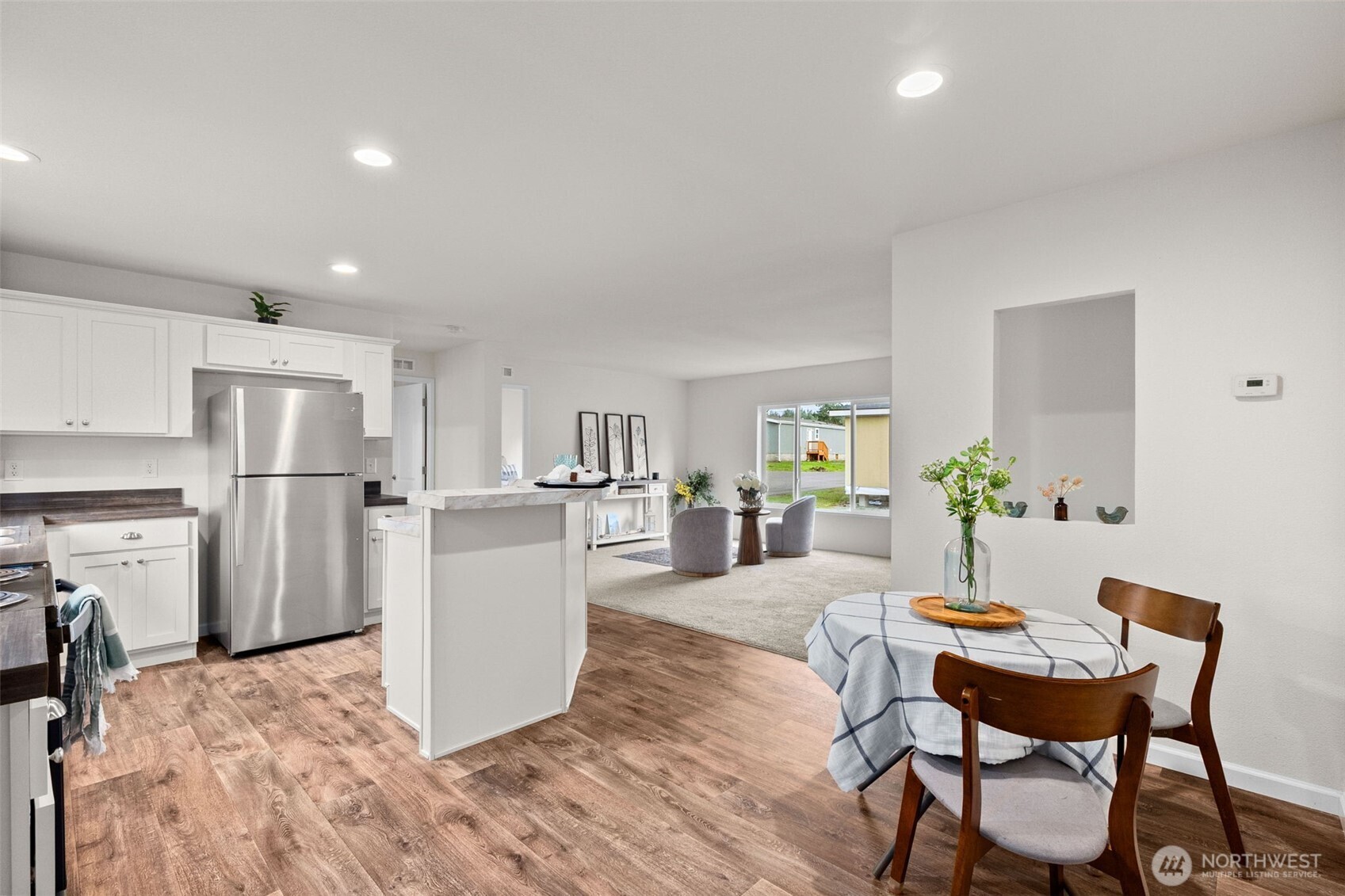 6748 Fir Tree Road Southeast, Unit 15 Olympia, WA 98513 - Photo 12 of 28 a living room with furniture and a dining table with kitchen view