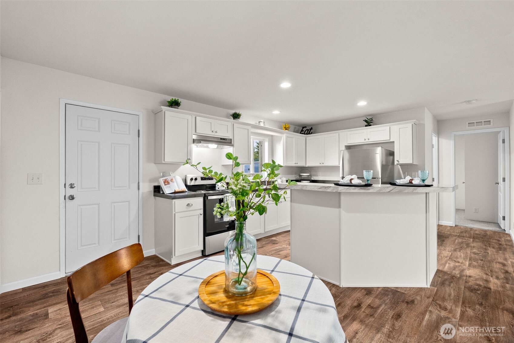 6748 Fir Tree Road Southeast, Unit 15 Olympia, WA 98513 - Photo 14 of 28 a kitchen with stainless steel appliances kitchen island granite countertop a refrigerator a stove a sink and white cabinets with wooden floor