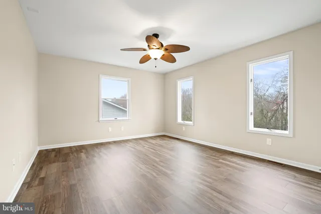 a view of an empty room with a window and wooden floor