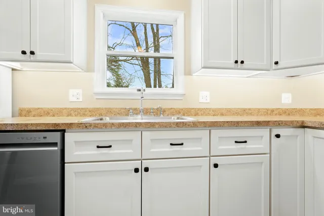 a bathroom with granite countertop white cabinets and a window
