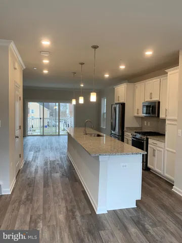 a large kitchen with stainless steel appliances kitchen island a large counter top a stove and a wooden floors