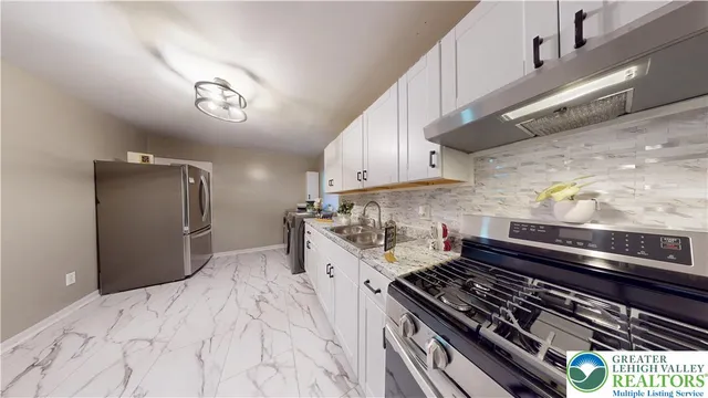 a large white kitchen with a sink dryer and refrigerator