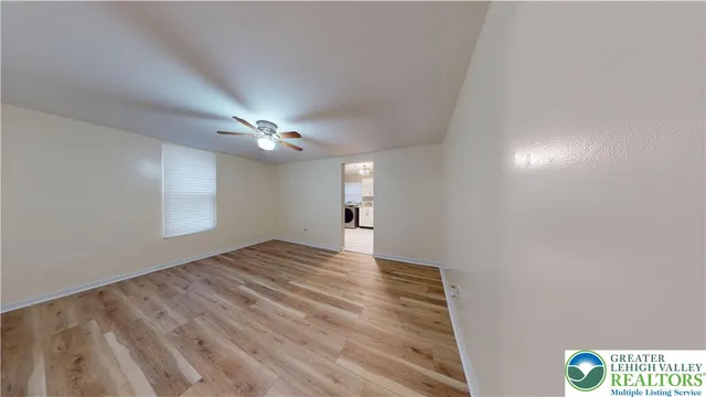 a view of an empty room and chandelier fan