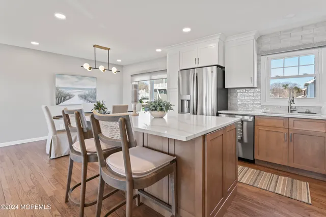 a kitchen with kitchen island granite countertop a dining table chairs refrigerator and cabinets