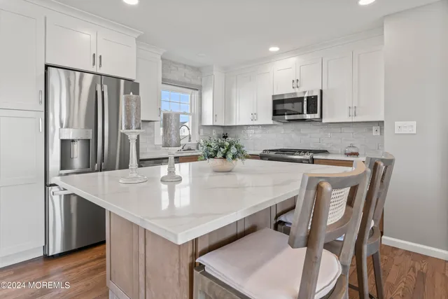 a kitchen with stainless steel appliances granite countertop a sink a microwave a stove and white cabinets