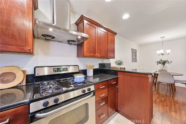 a kitchen with stainless steel appliances granite countertop a stove a sink dishwasher and cabinets with wooden floor
