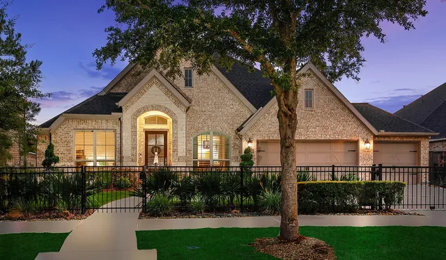 a front view of a house with a garden and a tree