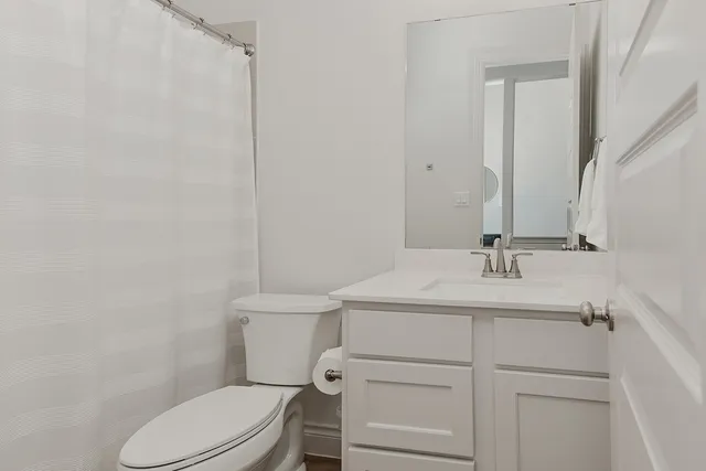a bathroom with a toilet sink vanity and mirror