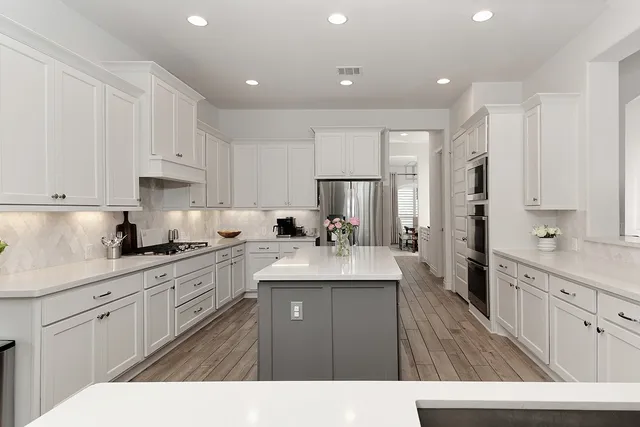 a kitchen with kitchen island white cabinets appliances and a sink