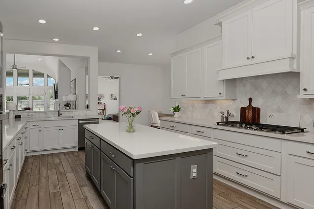 a kitchen with a sink dishwasher and white cabinets with wooden floor
