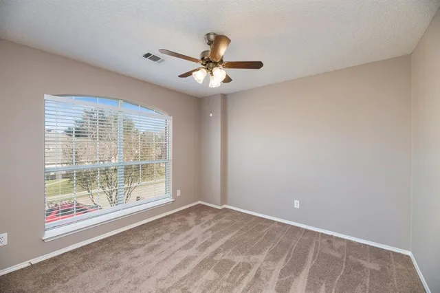 an empty room with windows and fan