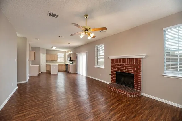 a view of an empty room with wooden floor and a fireplace
