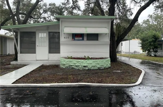 a view of a house with a small yard plants and large tree