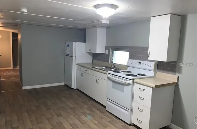 a kitchen with cabinets appliances and wooden floor