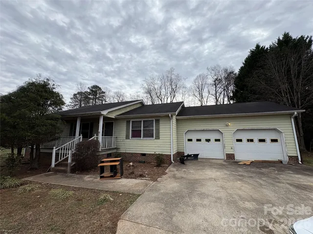 a view of a house with backyard and trees in the background