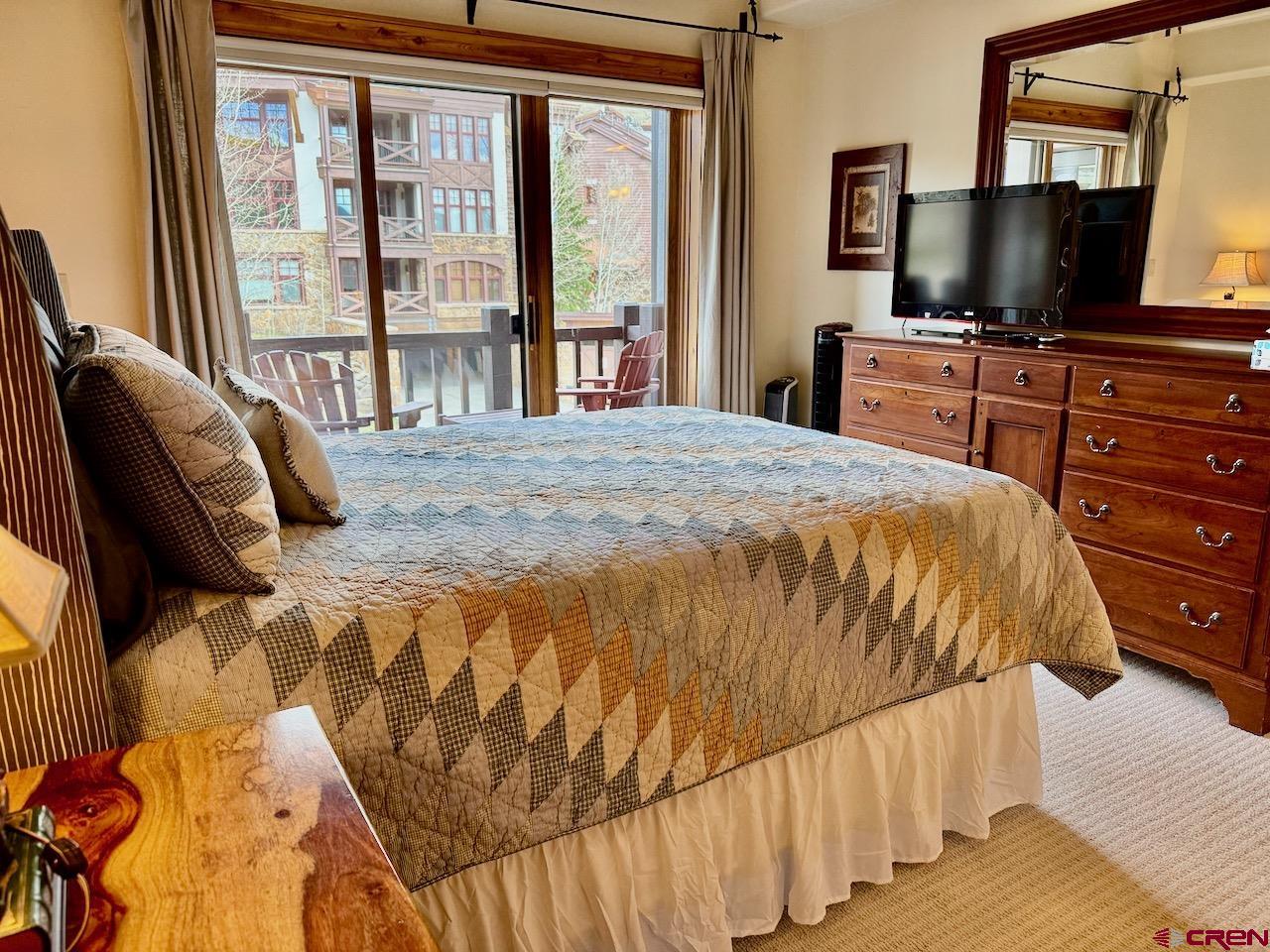 9 Hunter Hill Road, Unit 205 Crested Butte, CO 81225 - Photo 13 of 28 a bedroom with a bed and a flat tv screen on dresser