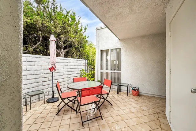 a patio with a table and chairs and potted plants