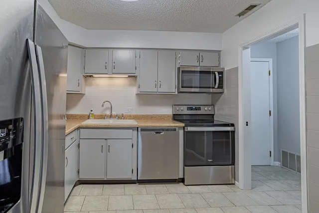 a kitchen with stainless steel appliances granite countertop a refrigerator and a sink