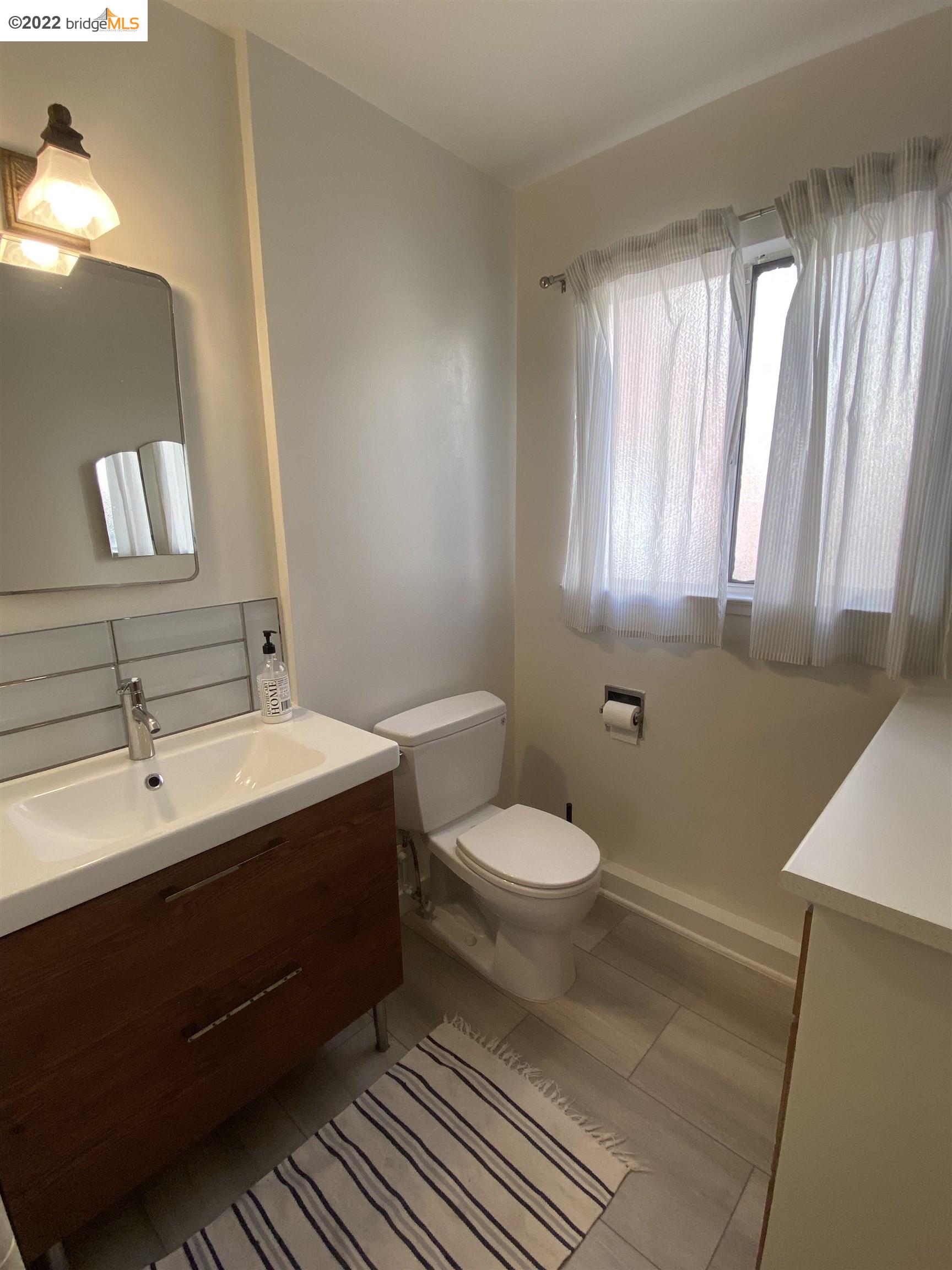 5357 Bryant Avenue Oakland, CA 94618 - Photo 16 of 26 a bathroom with a toilet sink and mirror