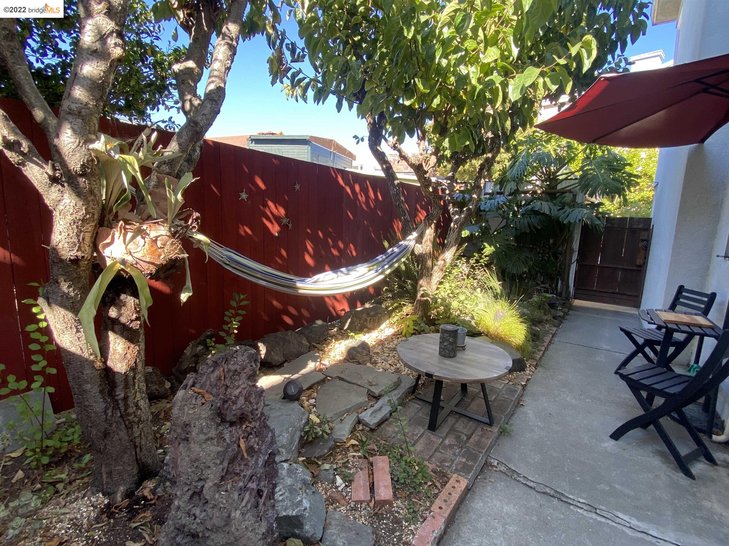 5357 Bryant Avenue Oakland, CA 94618 - Photo 21 of 26 a view of a backyard with table and chairs under an umbrella