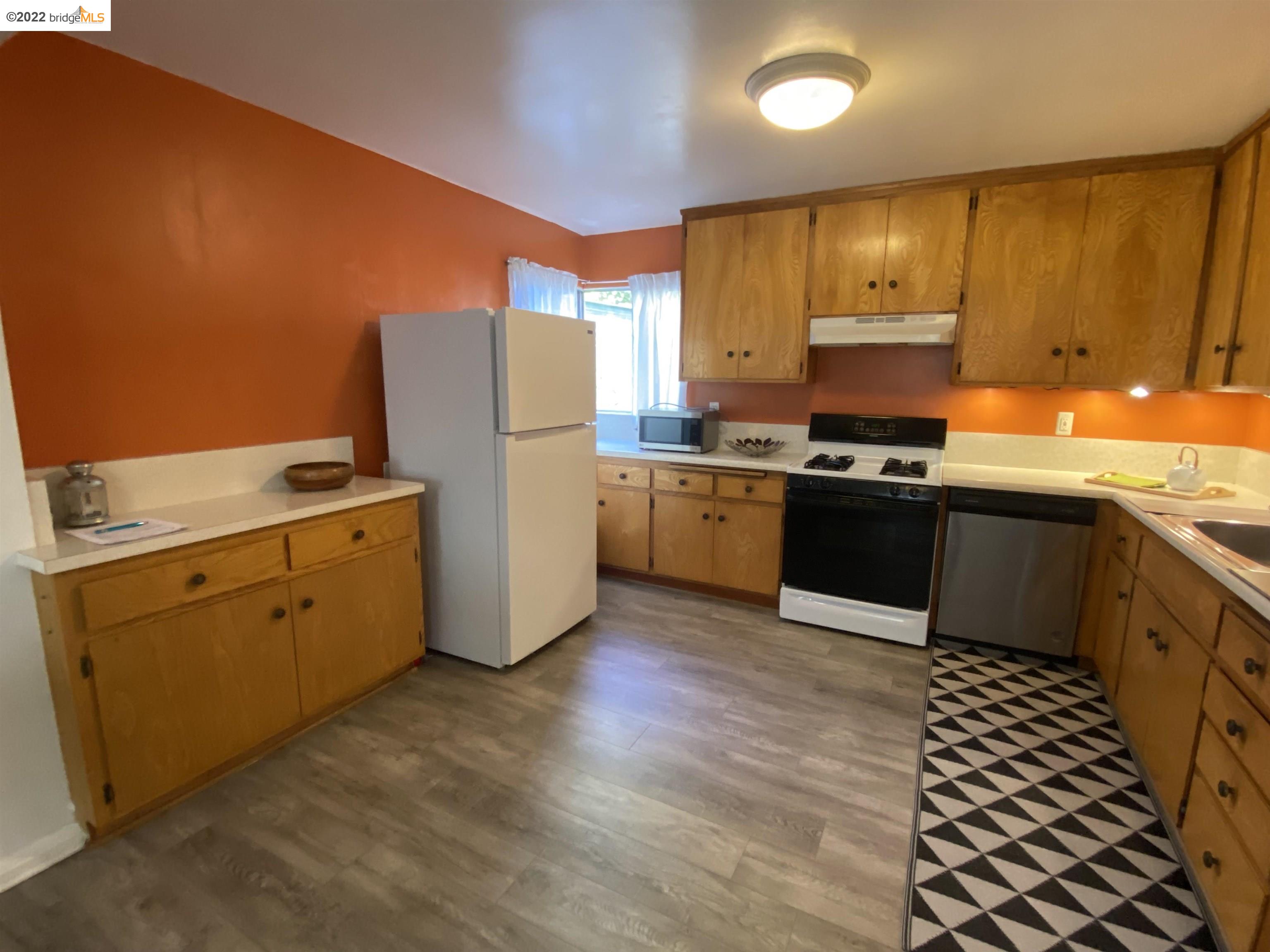 5357 Bryant Avenue Oakland, CA 94618 - Photo 5 of 26 a kitchen with stainless steel appliances a stove a sink a refrigerator white cabinets and wooden floor