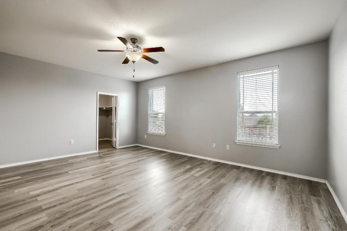 7308 Altidore Drive Austin, TX 78744 - Photo 11 of 24 Unfurnished bedroom featuring a spacious closet, light wood-style flooring, and ceiling fan