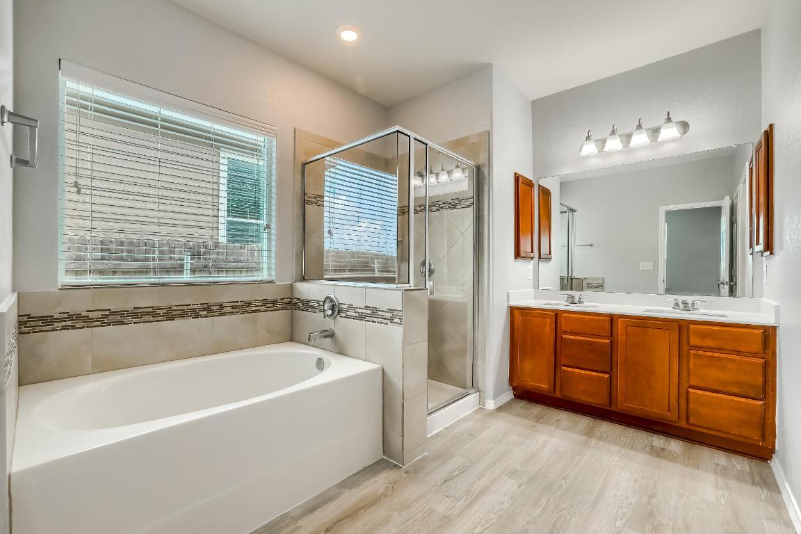 7308 Altidore Drive Austin, TX 78744 - Photo 12 of 24 Full bathroom with double vanity, a garden tub, light wood-style floors, and a stall shower