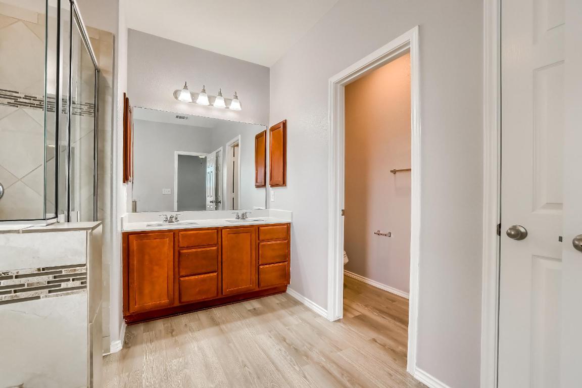 7308 Altidore Drive Austin, TX 78744 - Photo 13 of 24 Full bath with double vanity, a shower stall, and light wood finished floors