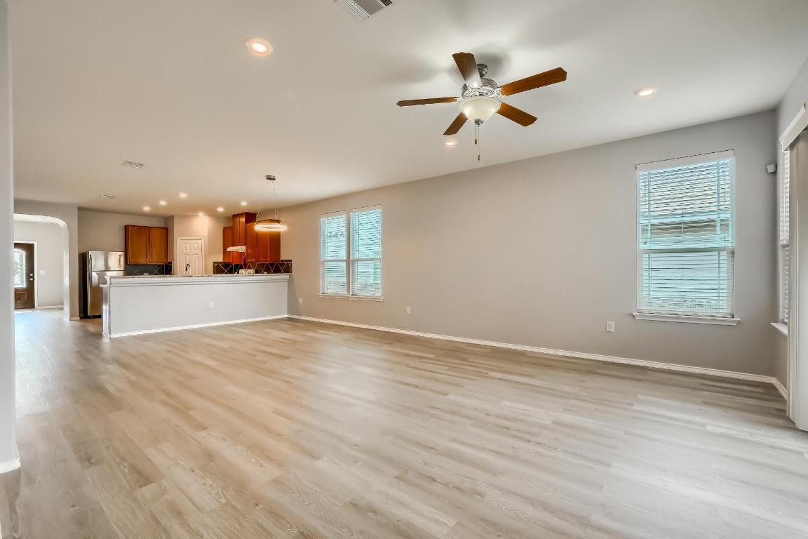 7308 Altidore Drive Austin, TX 78744 - Photo 4 of 24 Unfurnished living room with recessed lighting, arched walkways, light wood finished floors, healthy amount of natural light, and ceiling fan