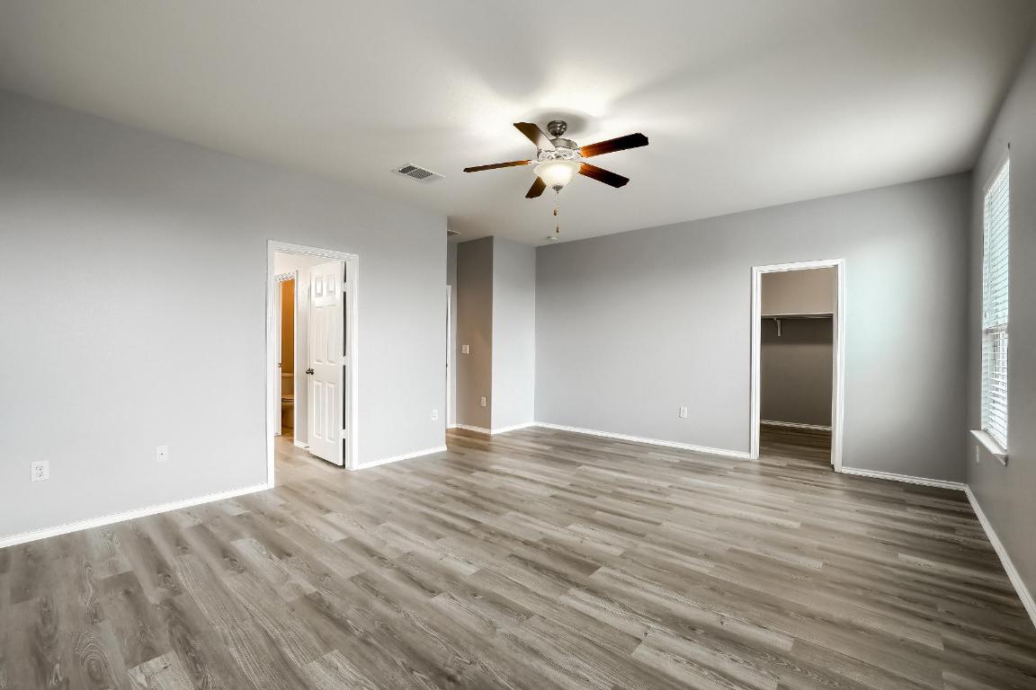 7308 Altidore Drive Austin, TX 78744 - Photo 10 of 24 Unfurnished bedroom with a spacious closet, light wood finished floors, and ceiling fan