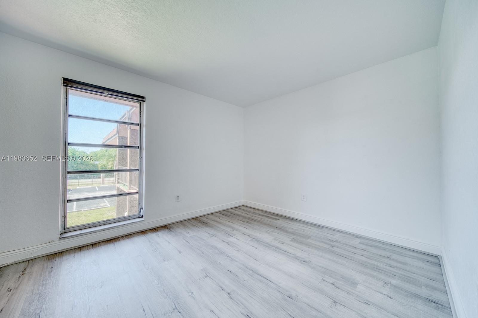 9459 Southwest 76th Street, Unit R5 Miami, FL 33173 - Photo 17 of 33 an empty room with wooden floor and window