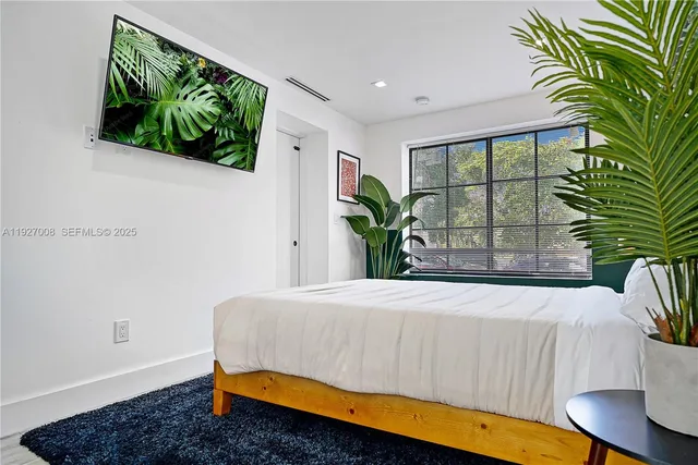 a bedroom with a bed a potted plant and a large window