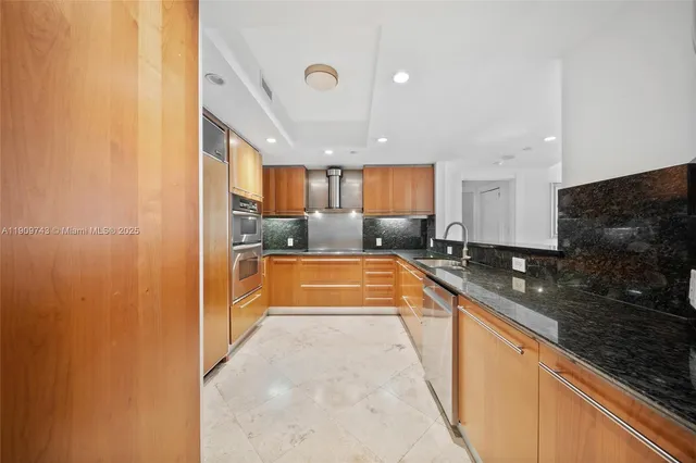 a large kitchen with stainless steel appliances a large counter top and a refrigerator