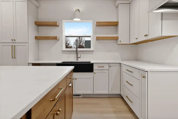 a kitchen with white cabinets and sink