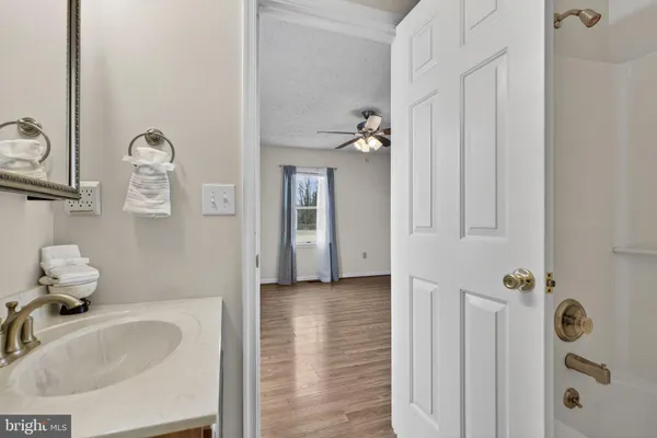 an empty room with wooden floor a ceiling fan and windows