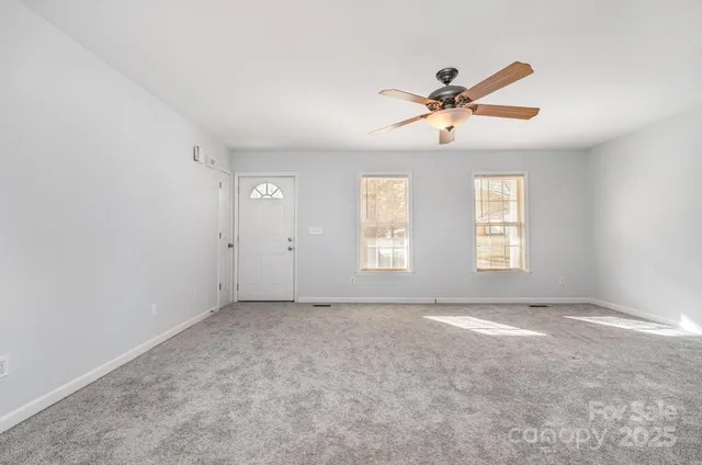 a view of a big room with windows and chandelier fan