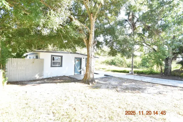 a backyard of a house with large trees and outdoor seating