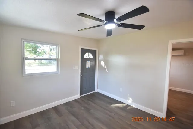an empty room with wooden floor fan and windows