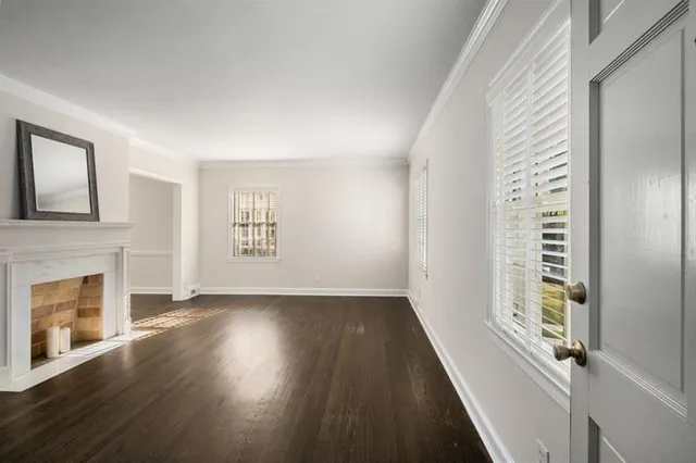 a view of an empty room with fireplace and wooden floor