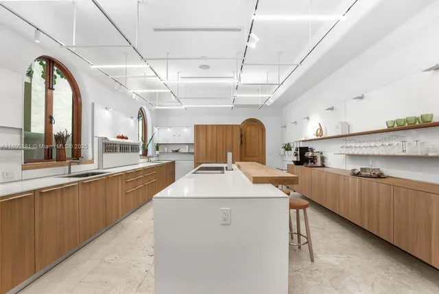 a large kitchen with kitchen island a large window a sink stainless steel appliances and windows