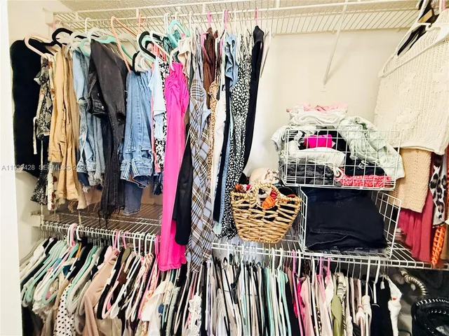 a view of walk in closet with clothes and shoes