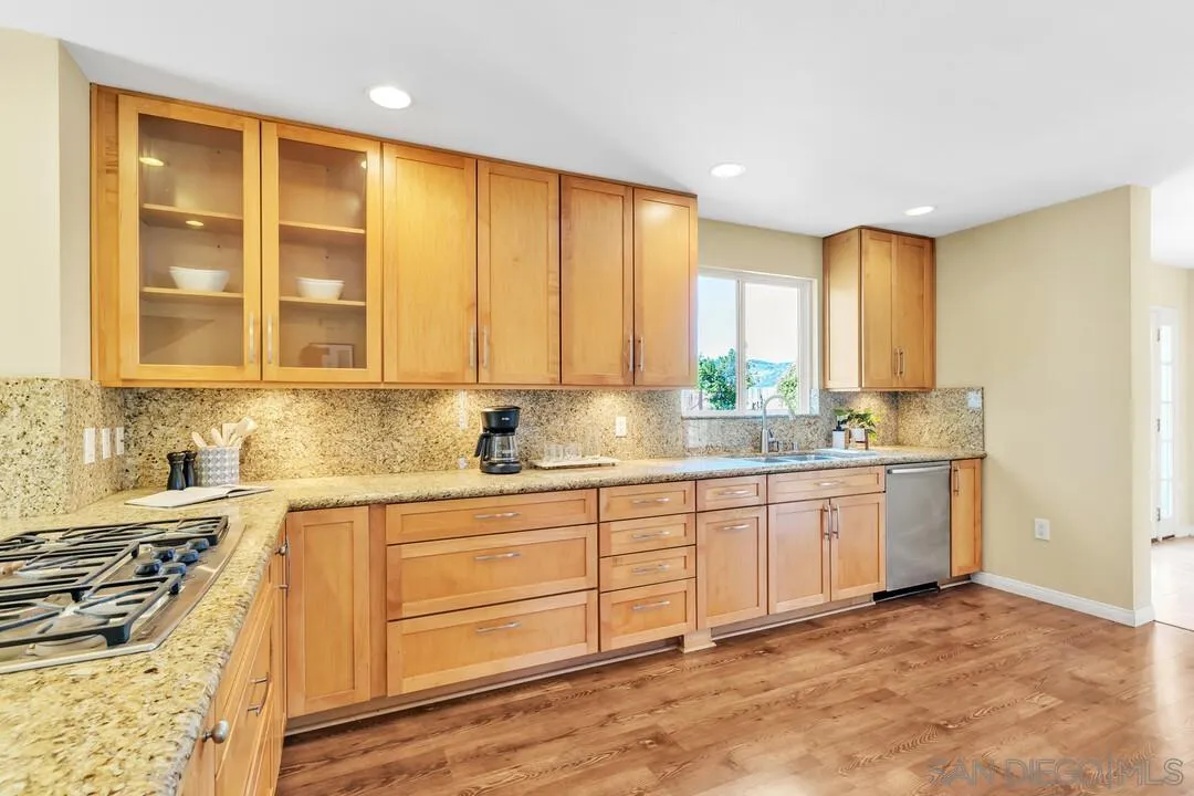 12232 Colony Drive Poway, CA 92064 - Photo 10 of 61 a kitchen with granite countertop wooden cabinets a sink a stove a window and stainless steel appliances